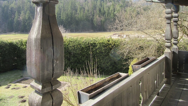 A wooden balcony with a view of a mountainous landscape.
