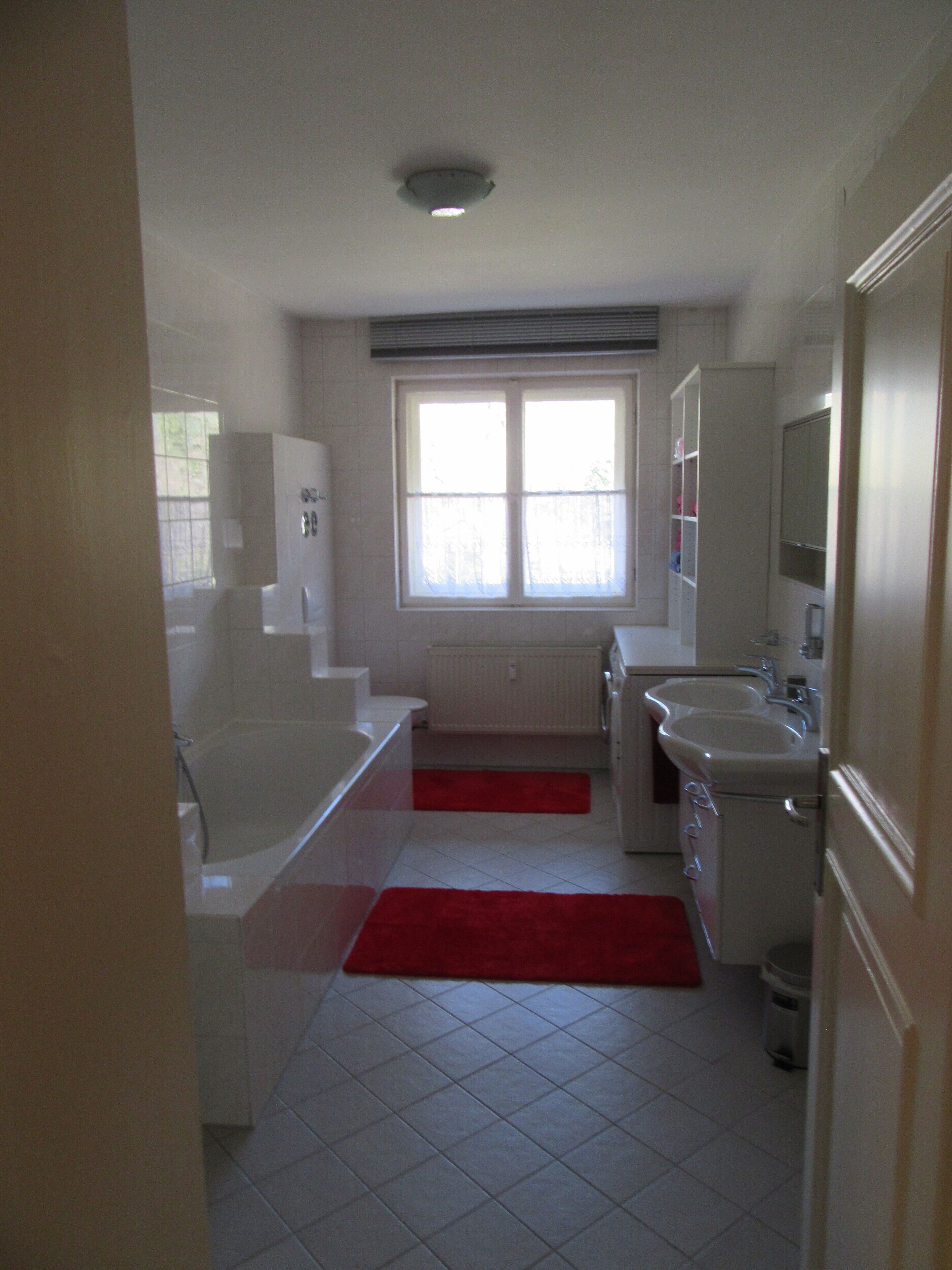Une salle de bain avec une baignoire, un lavabo et une fenêtre.