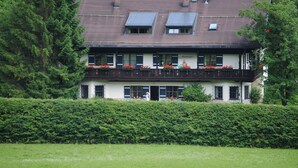 A two-story building with a balcony, large windows, and a roof with solar panels.