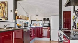 Uma cozinha moderna com armários vermelhos, uma ilha central, micro-ondas e pia.