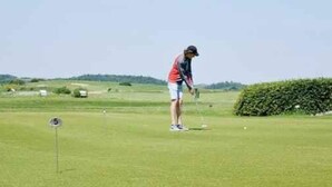 Uma pessoa em um campo de golfe com uma bandeira marcada '5'.