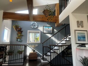Ein modernes Interieur mit Holzboden, einer Wanduhr, einem gerahmten Bild und einer Treppe.