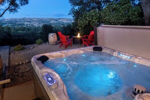 Un bain à remous doté d’une interface numérique, entouré de chaises rouges et agrémenté d’un foyer, offrant une vue imprenable sur un paysage magnifique.