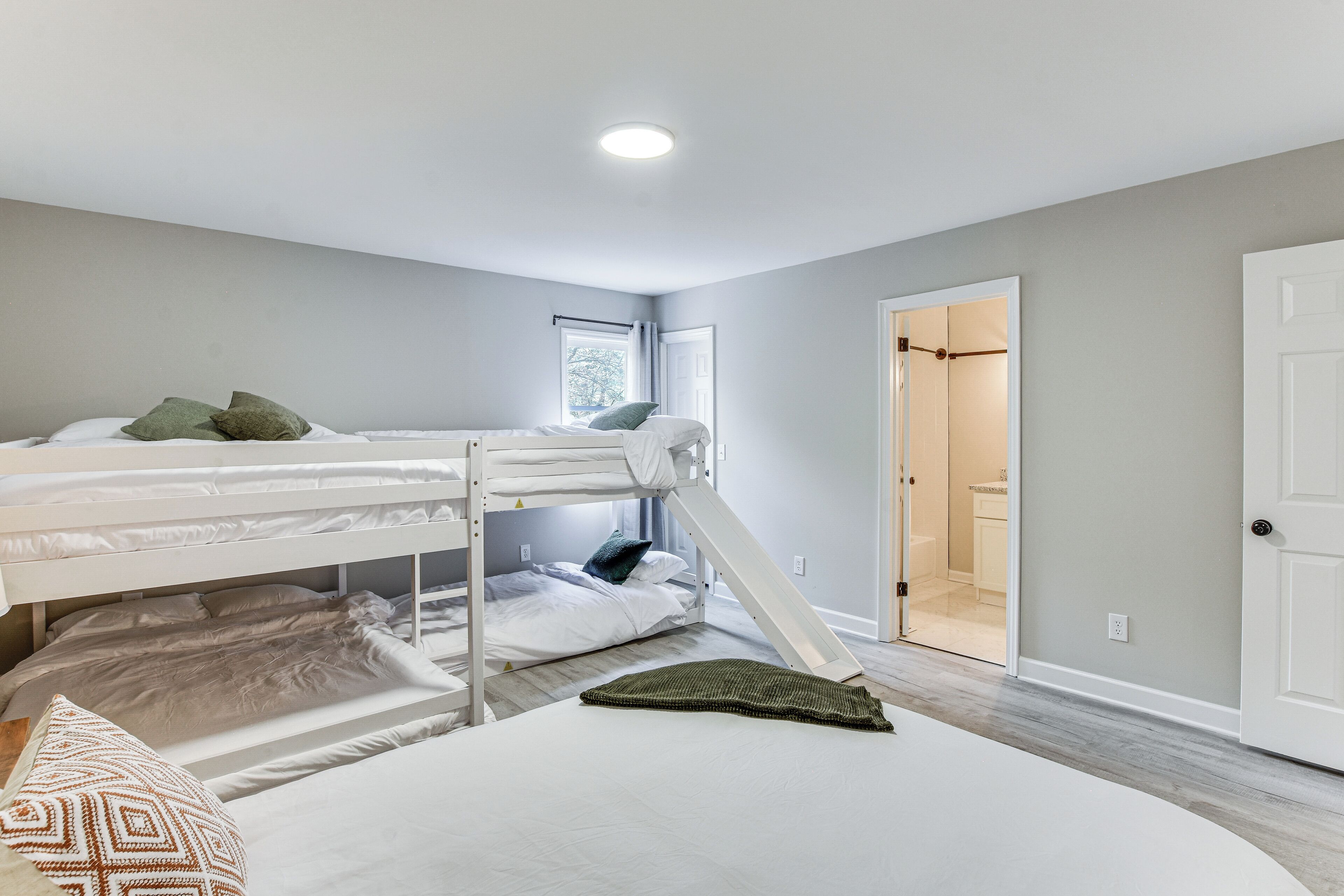 Une chambre avec un lit superposé, une fenêtre, une porte et un sol recouvert de moquette.