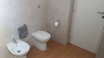 Een badkamer met toilet, bidet en wastafel.
