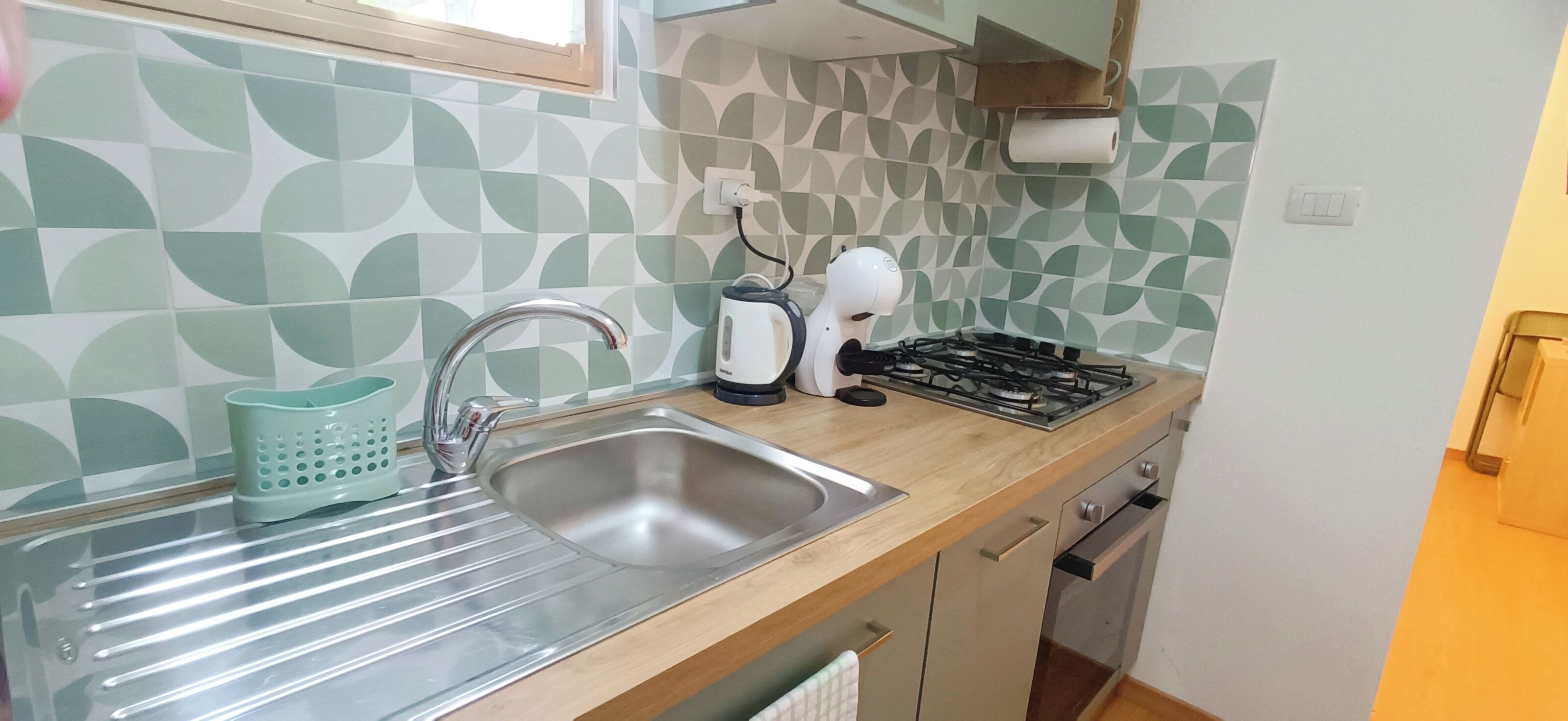 A kitchen with a stainless steel sink, a kettle, and a gas stove.