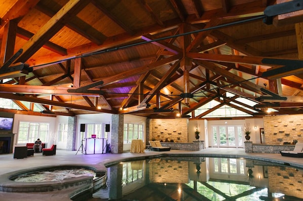 A spacious indoor swimming pool with a stone wall and wooden beams.