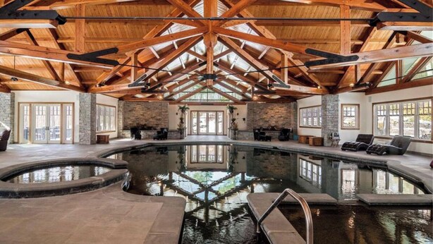 Une piscine intérieure avec un plafond en bois et des murs en pierre.
