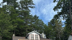 A two-story house with a balcony, surrounded by trees.