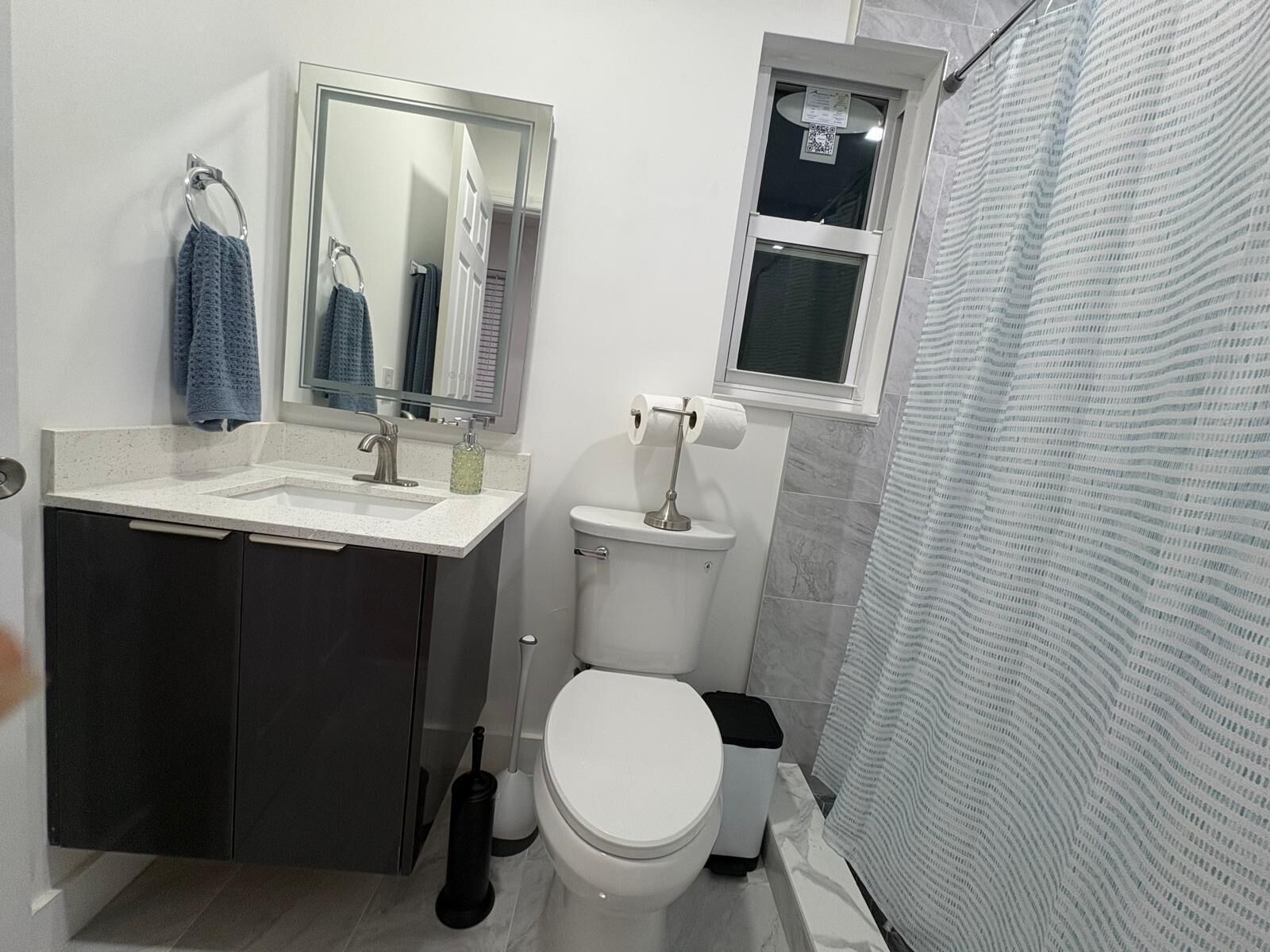 Une salle de bain équipée d’un lavabo, d’un miroir, de toilettes et d’un rideau de douche.