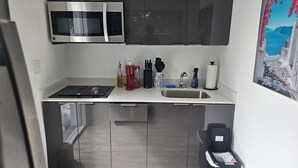Ett modernt kök med en mikrovågsugn i rostfritt stål, en kaffebryggare och en diskho.