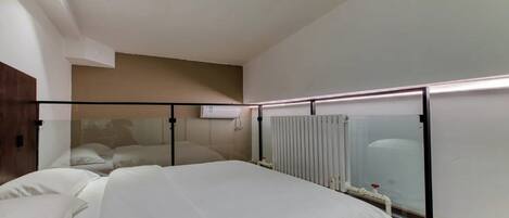 Una habitación de hotel moderna con una cama grande, un cabecero de madera, un radiador y una lámpara en el techo.
