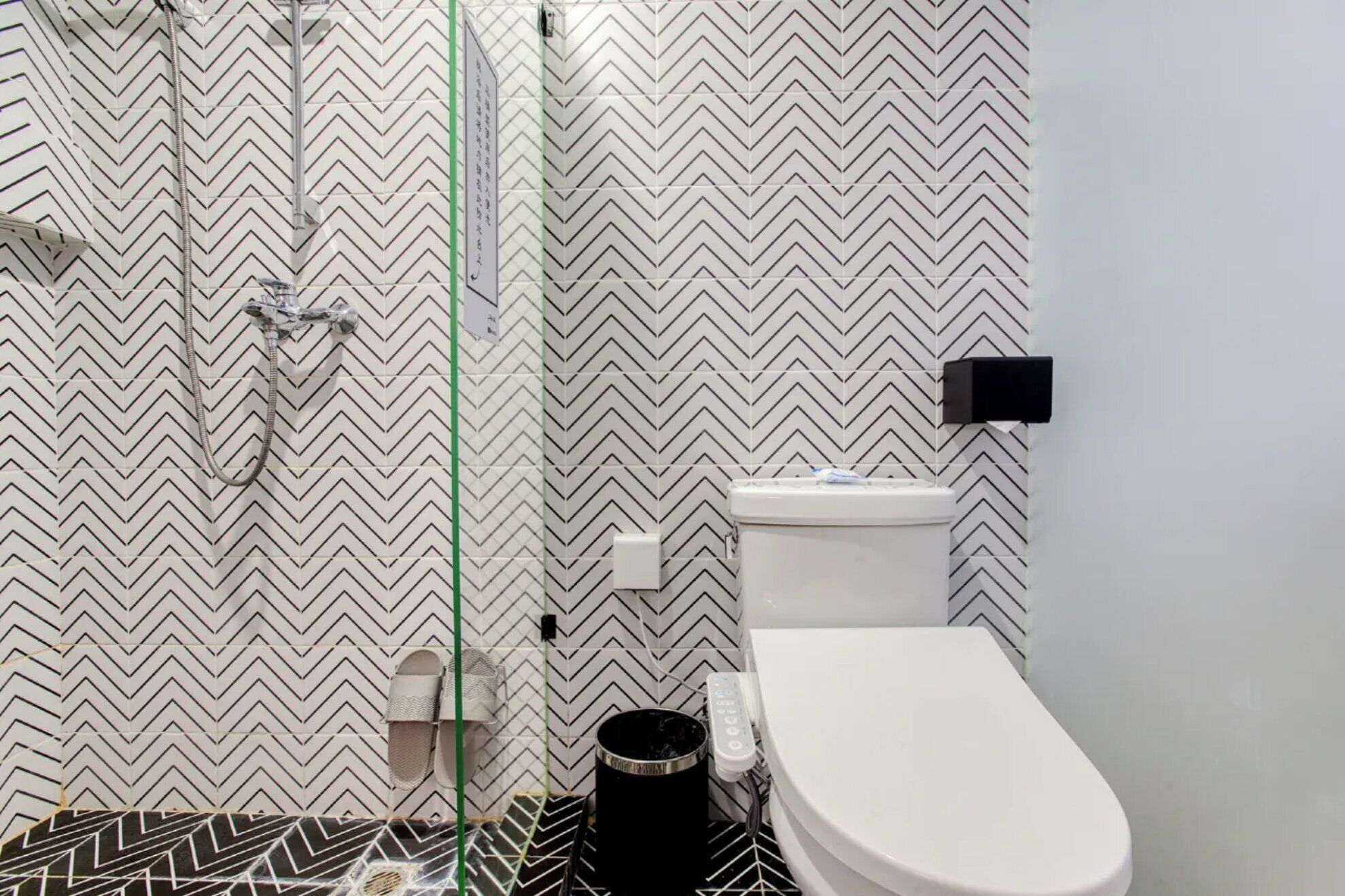 A bathroom with a zigzag patterned wall, a toilet, and a shower area.