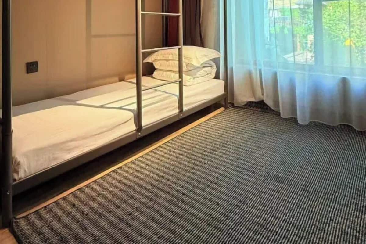 A bunk bed room with a window and curtains.
