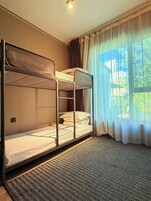 A bunk bed room with a window and curtains.