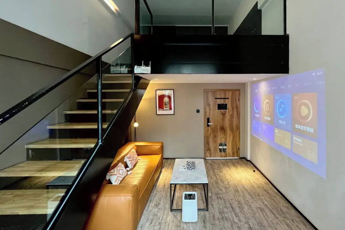 A modern interior with a staircase, a sofa, a coffee table, and a wall projection.