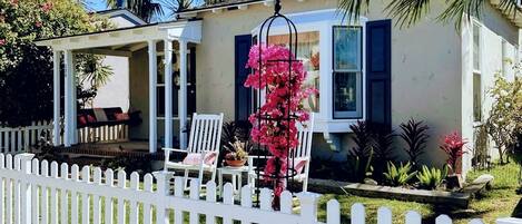 A house with a porch, white picket fence, and a garden.