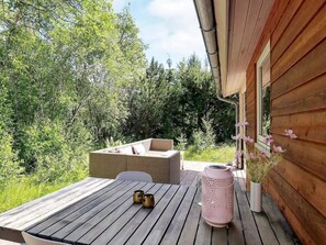 En träaltan med ett bord, två stolar, en soffa av rotting och en rosa lykta.