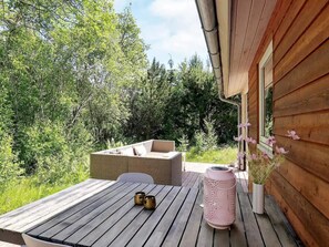 A wooden deck with a table and chairs, a wicker sofa, and a pink lantern. - 4 Star Holiday Home in Albaek (Aalbaek)