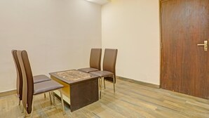 A room with a wooden door, a table with chairs, and a patterned tablecloth. - Super Deluxe Room Hotel Kuber Inn (Dhanbad)