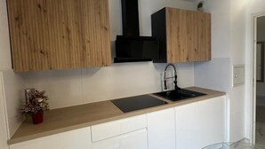 Une cuisine moderne avec des meubles en bois, une hotte noire, un évier et un plan de travail en marbre.