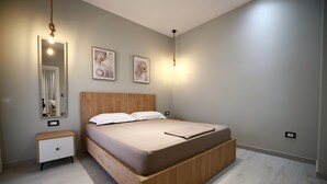 Une chambre à coucher avec un lit en bois, une table de chevet, un miroir et des lampes fixées au mur.