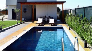 Une maison moderne à deux étages, dotée d’une piscine, d’un espace salon extérieur et d’un patio couvert.