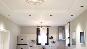 Une cuisine moderne avec un coin repas, un canapé et un luminaire suspendu au plafond.
