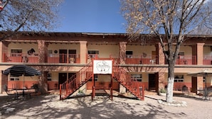 Un edificio de dos pisos con una escalera central, asientos exteriores y un letrero que indica un albergue.