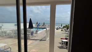 A pool area with lounge chairs and umbrellas, a view of the ocean, and a 'Welcome' sign.