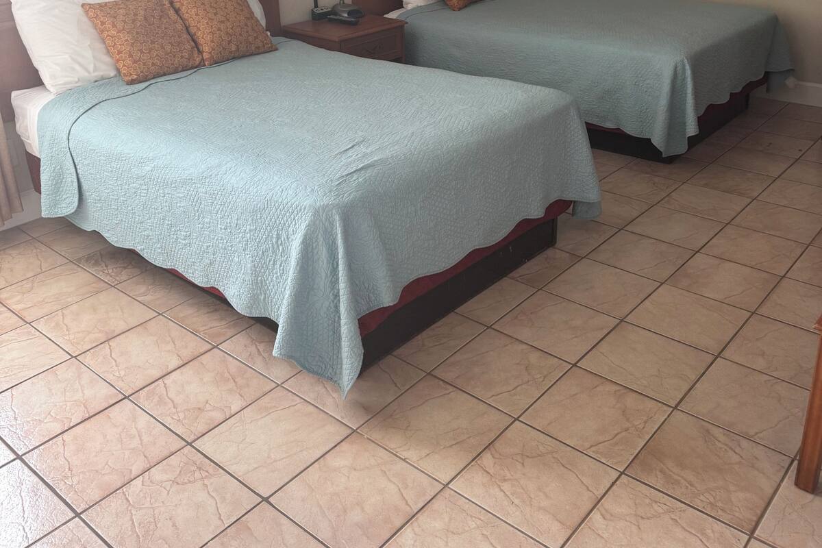 Una habitación de hotel con dos camas, una mesita de noche, una lámpara y obras de arte en las paredes.