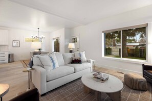 Ein modernes Wohnzimmer mit einer Couch, einem Couchtisch und einem großen Fenster.
