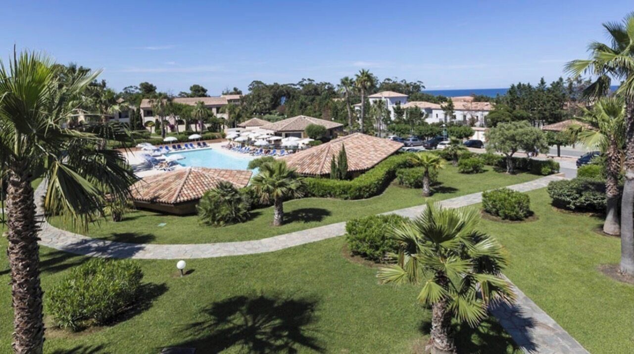 Ein Resort mit Swimmingpool, Palmen und freiem Blick auf den Ozean.