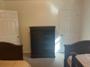 A bedroom with two wooden beds, a dark dresser, and two white doors.