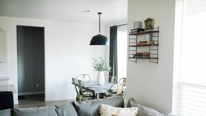 A modern living room with a grey sofa, a dining table with chairs, a hanging pendant light, and a bookshelf. - Spacious 5-bedroom house in lovely Twin Falls with AC (Twin Falls)