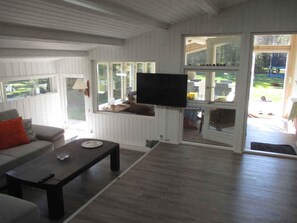 A living room with a sofa, coffee table, and a TV mounted on the wall. - 4 Star Holiday Home in Sjaellands Odde (Sjællands Odde)