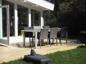 A covered patio with a table and chairs, a grill, and a lawnmower. - 4 Star Holiday Home in Sjaellands Odde (Sjællands Odde)