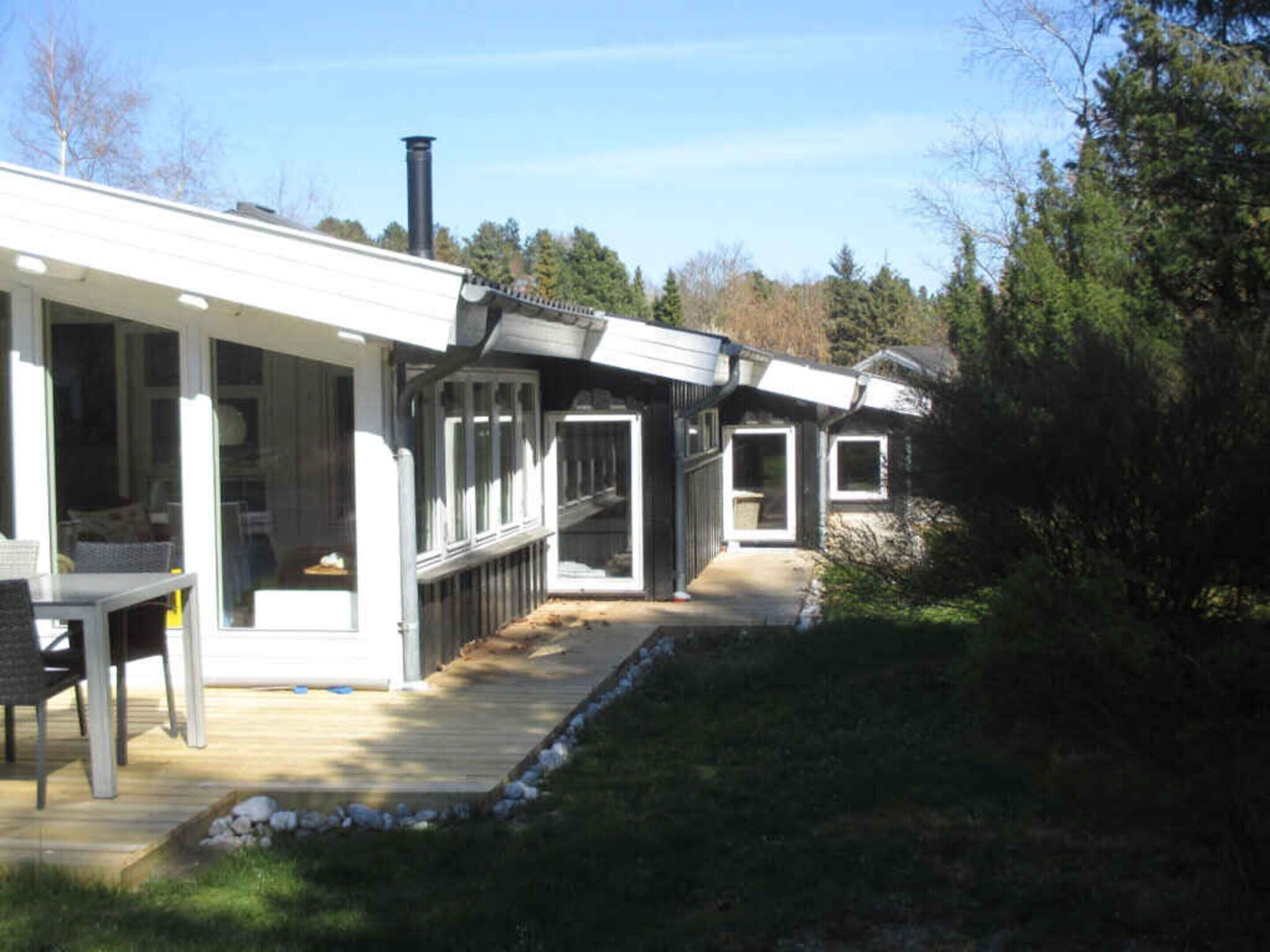 A modern house with a covered patio, a chimney, and a deck leading to the house.