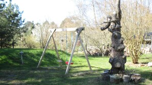 Una zona amb gespa, un tobogan i un tronc d'arbre.