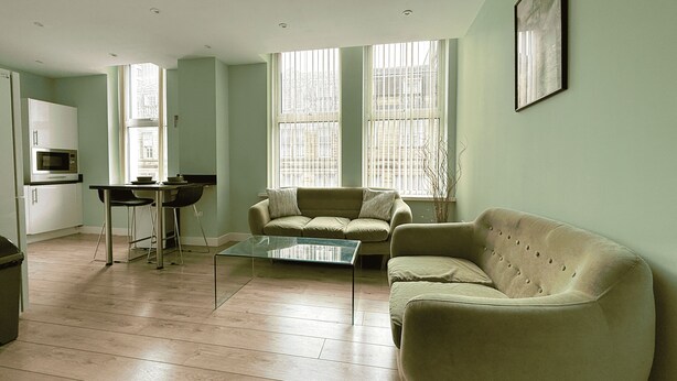 A living room with a sofa, a coffee table, and a dining area with a table and chairs. - Beautiful 2 bed Flat in City Centre (Sheffield)