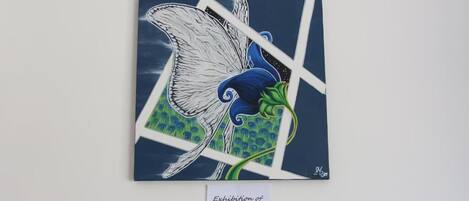 Obra enmarcada titulada 'Exposición de Artista Local' que presenta un pájaro estilizado con colores azul y verde.