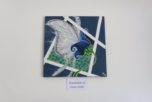 Obra enmarcada titulada 'Exposición de Artista Local' que presenta un pájaro estilizado con colores azul y verde.