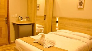 Una habitación de hotel con una cama, un escritorio pequeño, un espejo y una mesita de noche.