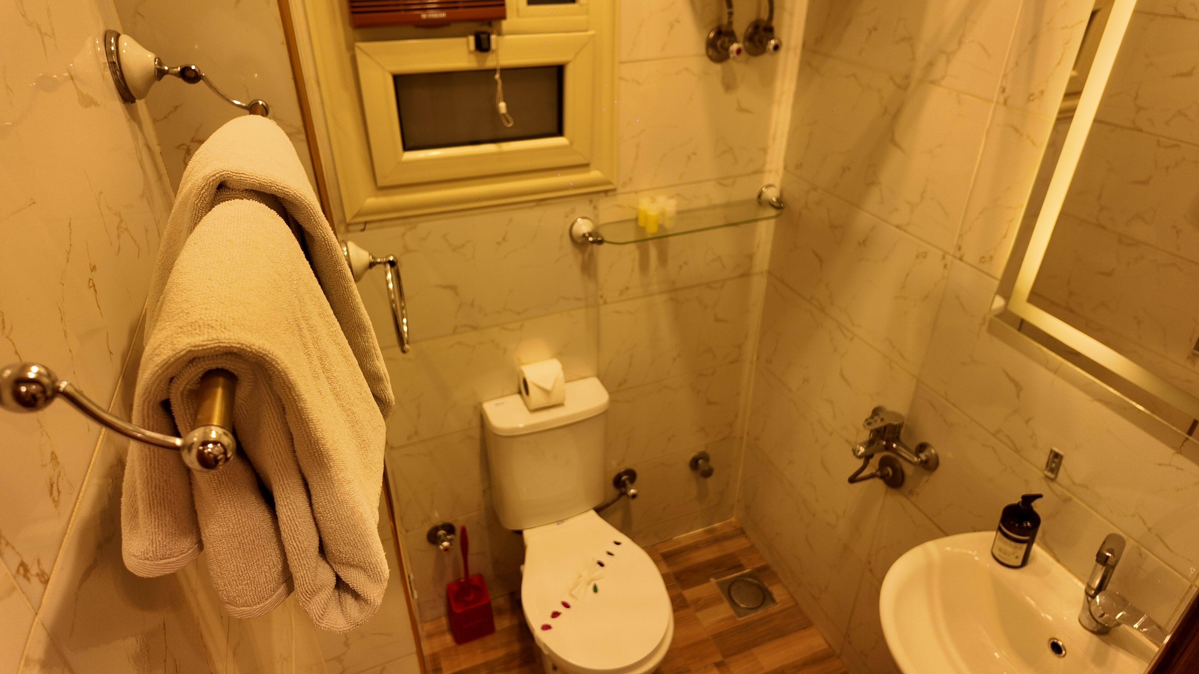 Un baño con inodoro, lavabo y toallero.