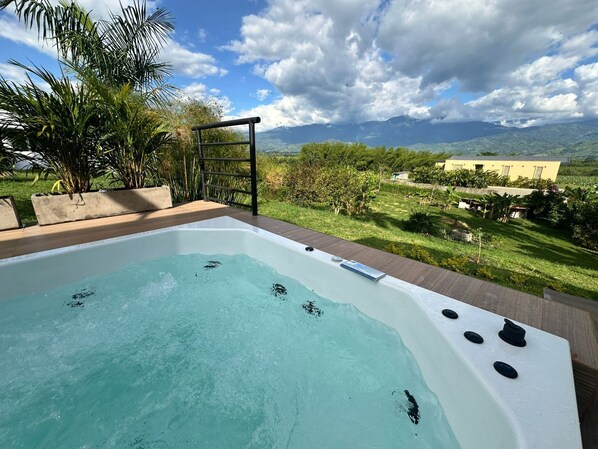 Un jacuzzi con vistas a montañas y un jardín.