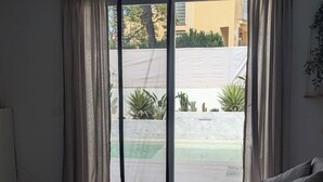 Una sala moderna con sofá, puerta corrediza de vidrio a un patio interior y una planta en maceta.