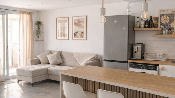 Una cocina moderna con barra, refrigerador y cafetera.