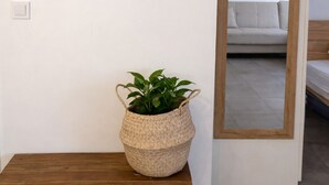 Una habitación con un banco de madera, una cesta tejida con una planta y tres tapices de pared tejidos.