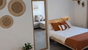 Un dormitorio con cama, un espejo, una lámpara colgante y un aire acondicionado instalado en la pared.
