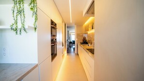 A modern kitchen with white cabinetry, a countertop, and hanging greenery. - Casa Marmite Sea View (Matosinhos)